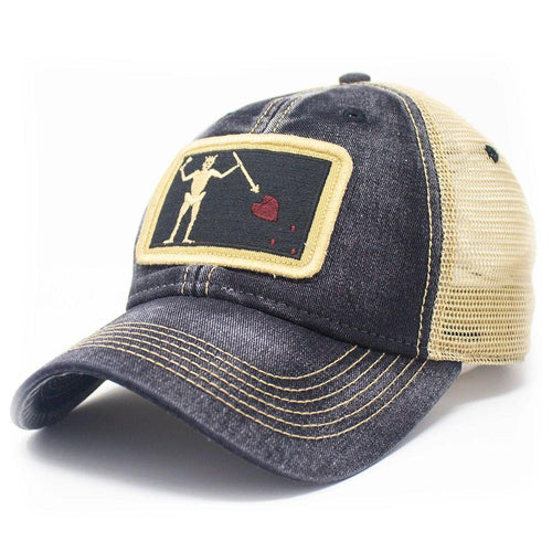 Black trucker hat with embroidered Blackbeard pirate flag patch on the center and khaki mesh back panels. Patch depicts a natural colored skeleton with horns piercing a red bleeding heart with a spear.