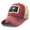 Brick red cotton trucker hat with khaki colored mesh backing and bill with tan stitching. Ballcap is embroidered with the South Carolina flag. Patch depicts a natural tone palm tree and moon on a rectangular bed of dark blue.