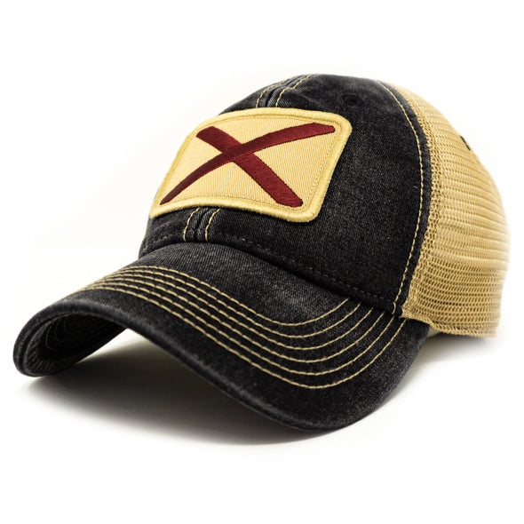 Black colored trucker hat with khaki mesh panels on the back and tan stitching. Ballcap is embroidered with the Alabama flag. The patch depicts a red X inside of a natural pigmented rectangle.
