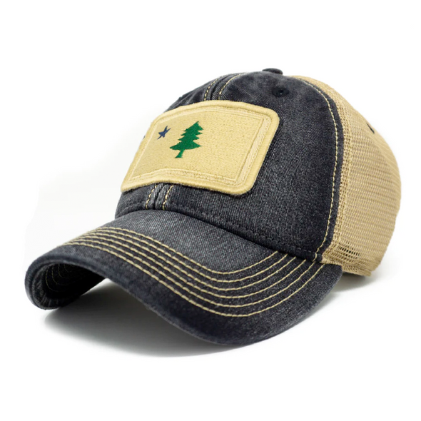 Black cotton trucker hat with khaki colored mesh backing and bill with navy stitching. Ballcap is embroidered with the 1901 Maine flag. Patch depicts a natural tone with a green pine tree and dark blue star.