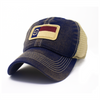 Kid Trucker hat with khaki colored mesh backing, denim cotton front panel and bill with tan stitching. Children&#39;s ballcap has an embroidered patch of the North Carolina flag in in the center.
